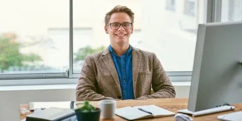 A confident professional man sits at a desk with a computer, representing the qualities of good public policy