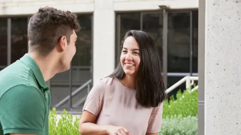A male student chats with a female peer outdoors on campus, representing reasons to study public policy online