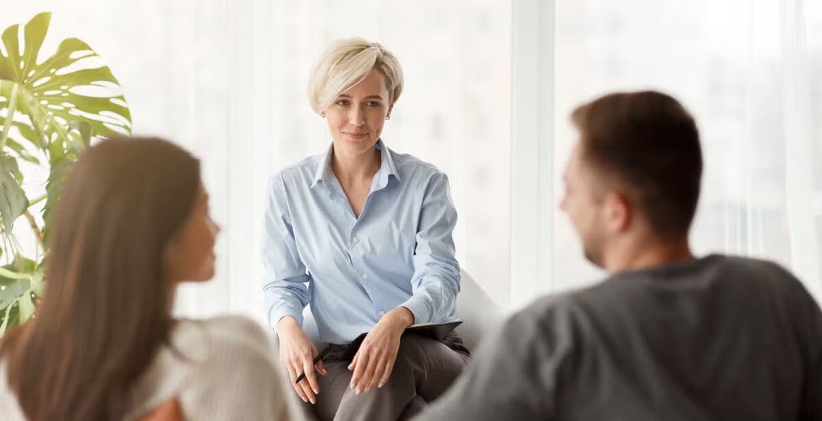 A counsellor sits calmly across from a couple, representing the supportive role of a counsellor
