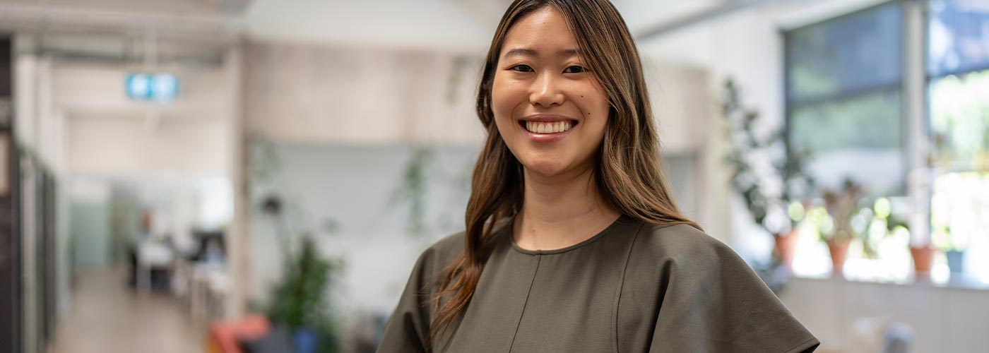 A smiling young woman sitting at her desk in a bright office environment.
